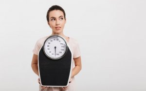 Ragazza esile con una bilancia nelle sue mani.