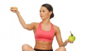 donna che regge un hamburger e una mela