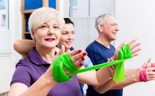 Tre persone fanno esercizi per le braccia con l'elastico