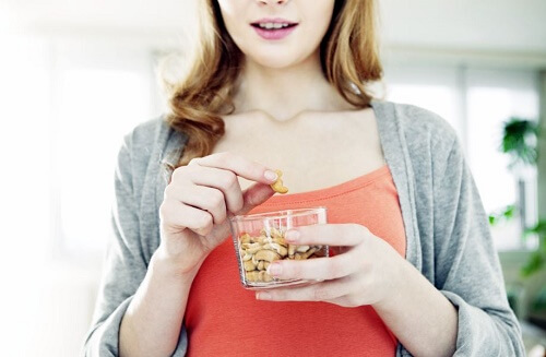 una ragazza intenta a mangiare della frutta secca