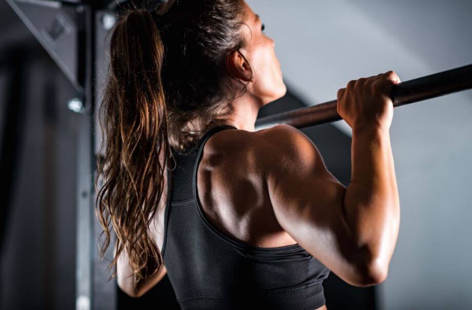 ragazza fa trazioni in un programma di allenamento intenso