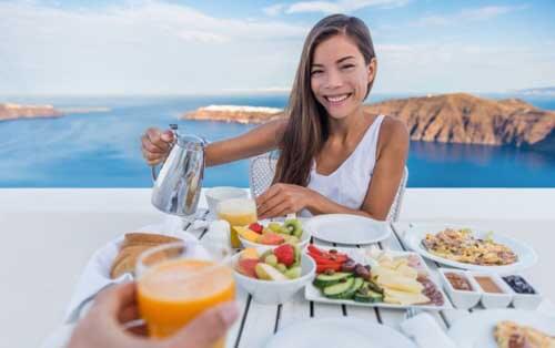 Ragazza fa colazione davanti al mare