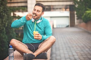 sportivo che mangia frutta seduto sul muretto