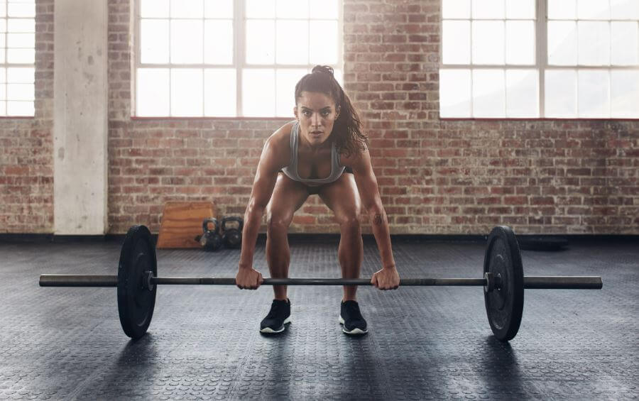 Ragazza che esegue il deadlift tra gli esercizi base del crossfit