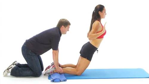 Donna che si allena con il personal trainer. Esercizi muscoli ischiocrurali.