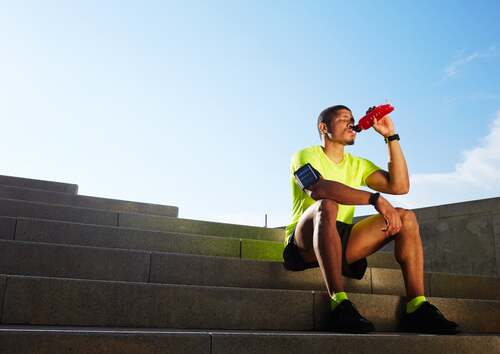 Atleta che beve seduto sulle scale.