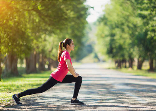 Donna fa stretching alle gambe nel parco.