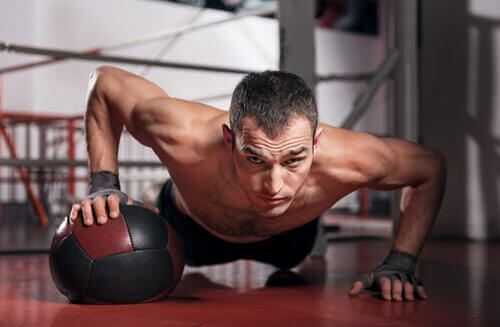Uomo fa flessioni con la palla medica.