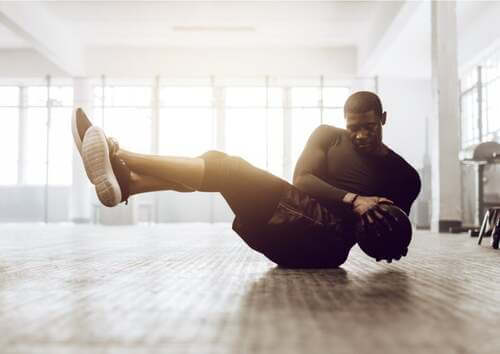 Uomo che esegue il russian twist con la palla medica.