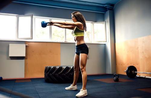 Ragazza che esegue kettlebell swing per bruciare calorie.