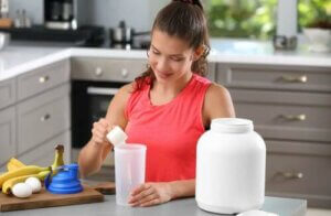 Ragazza che si prepara un frullato con gli integratori prima dell'allenamento.